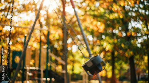 An artistic bokeh shot of a playground with an empty swing set moving slightly in the breeze under a warm afternoon sun.