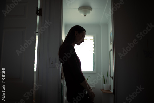 silhouette of tired woman leaning against wall in bathroom, stress and mental health concept
