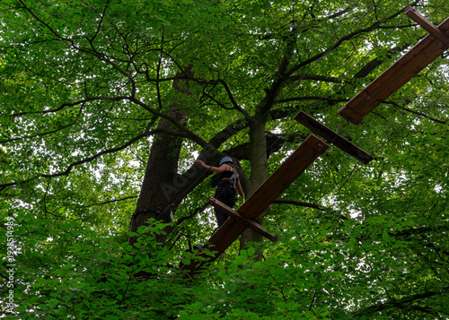 Active girl balancing on wooden beam in high ropes course