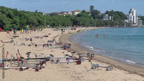 AUCKLAND, NEW ZEALAND – 22 February 2026: People enjoy a sunny day at Kohimarama Beach. Some are swimming, playing volleyball, and relaxing on the sand.