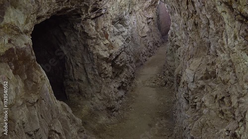 Mysterious dark cave interior revealing ancient rocky walls and shadowy underground chamber passage. Dramatic creepy cavern hall with textured stone formations creating eerie atmospheric environment.