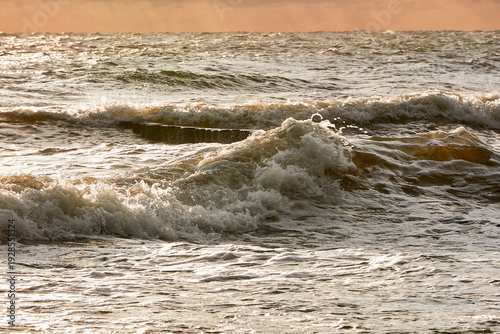 Fotografie Waves Crashing on a Wooden Groin at Sunset in the Baltic Sea