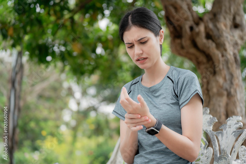 Young woman feeling numbness and tingling in fingers after outdoor workout in park, holding painful wrist, nerve pain and neuropathy health concept. numbness, tingling, fingers, nerve, neuropathy.