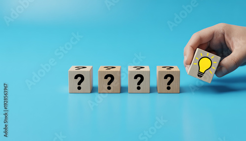 Hand holding a lightbulb cube among question mark cubes on a blue background