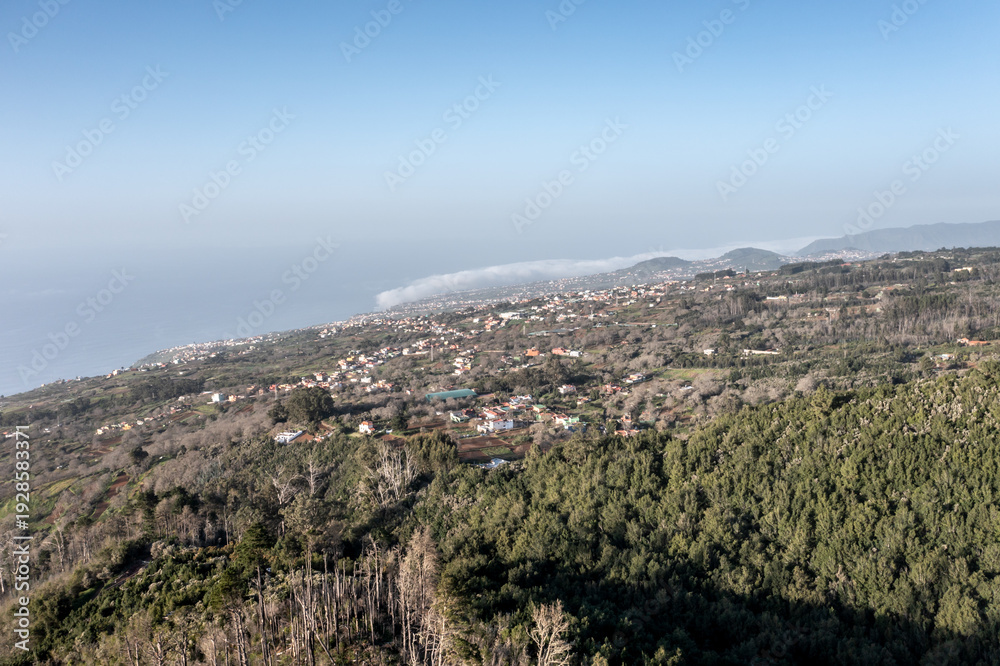 Obraz premium Aerial view of Tenerife forest meeting the ocean coastline with coastal villages below
