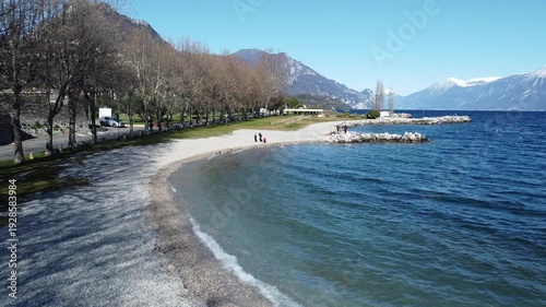 Pebble beach in Toscolano Maderno with snowy mountains and Lake Garda, Italy