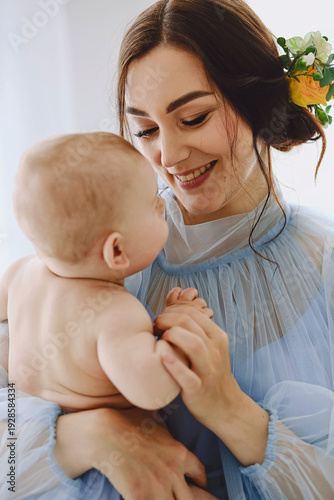 Close up portrait of smiling mother and baby, emotional bonding moment, woman in light blue tulle dress