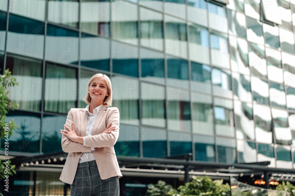 Fototapeta premium Smiling businesswoman standing confident in corporate building exterior