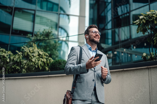 Foto Happy businessman using smartphone and wireless earbuds