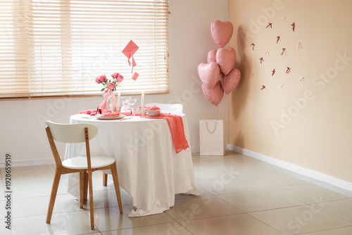 Interior of room with dining table set for Valentine's Day, letters and balloons