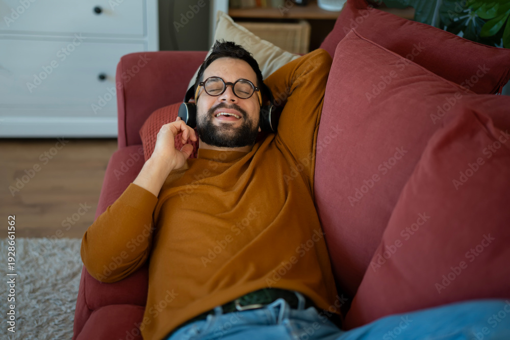 Fototapeta premium Young man relaxing on couch listening to music