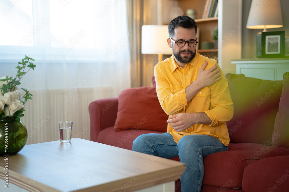 Obraz premium Young man feeling shoulder pain at home