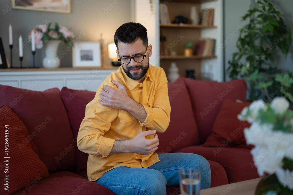 Obraz premium Man feeling shoulder pain and discomfort at home