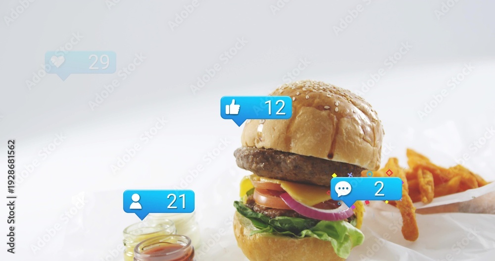 Fototapeta premium Showcasing stacked cheeseburger on white paper at studio, with fries, glass jars, reaction badges