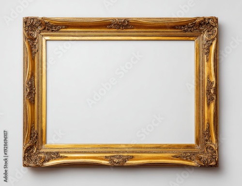 An ornate golden picture frame with intricate carvings is empty on a white wall