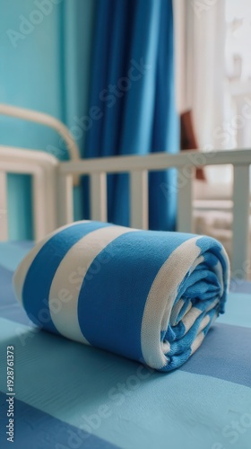Rolled blue and white striped blanket on a bed.