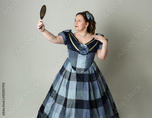 Obraz na plátně portrait of Victorian Era Woman in historical victorian classical Blue Ball Gown costume, Plus Size Model, holding antique hand mirror