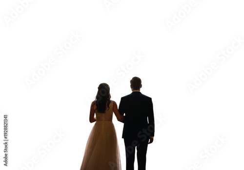 A couple stands together in a dimly lit room with their backs to the camera.raced