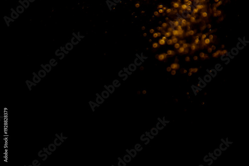Abstract blurred golden bokeh lights against a dark background, creating a dramatic and festive atmosphere with glowing and shimmering effects, perfect for holiday and celebration themes.
