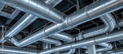 Industrial metal ventilation ducts intertwined in a ceiling space of a commercial building.