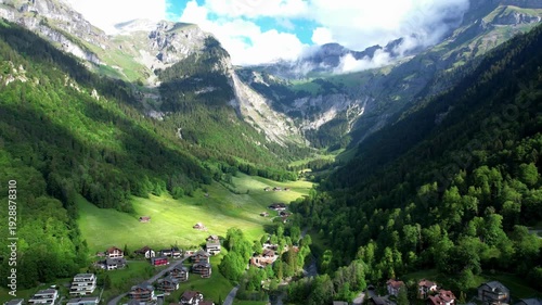 Breathtaking Aerial view of alpine village in lush green mountain valley at Switzerland, the  beauty of nature dramatic play of light and shadow across the slopes, with a dense forest.