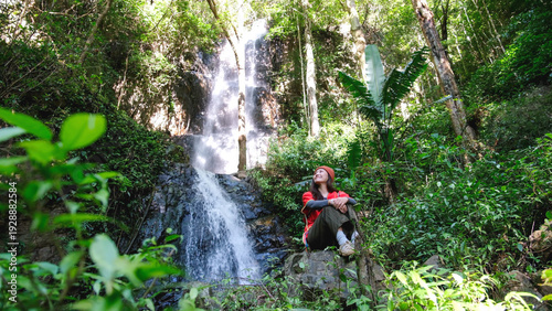 Foto Portrait image of a woman sitting in front of the waterfall in the forest