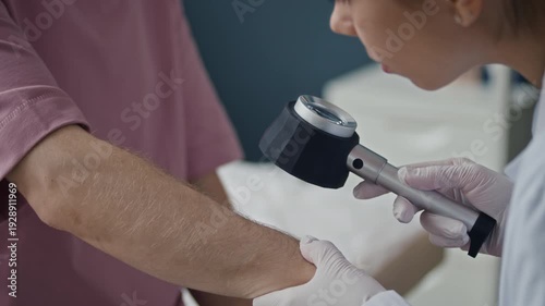 B roll closeup of female dermatologist conducting melanoma screening on male patient arm using dermatoscope