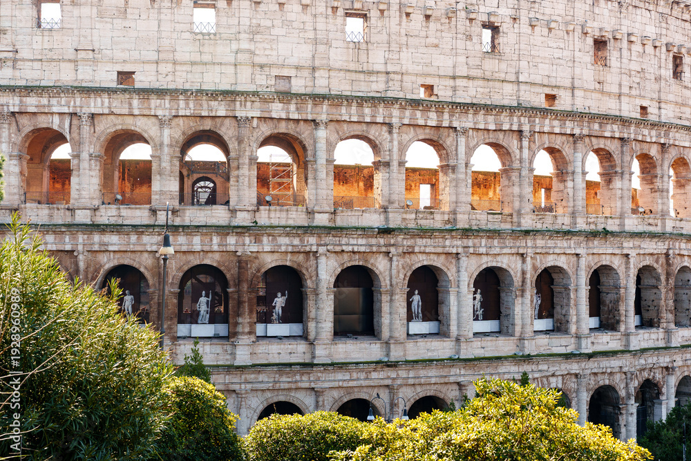 Fototapeta premium Visitors explore the Colosseum in Rome during the daytime with sculptures in view