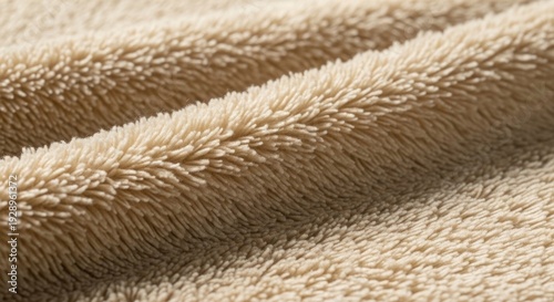 Soft, fluffy beige fabric texture with warm, cozy folds, ideal for backgrounds and textiles.