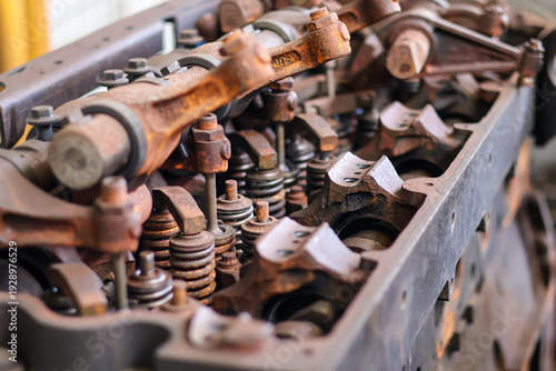 ​Close-up of rusty vintage engine valve train with rocker arms and springs in a mechanical workshop.