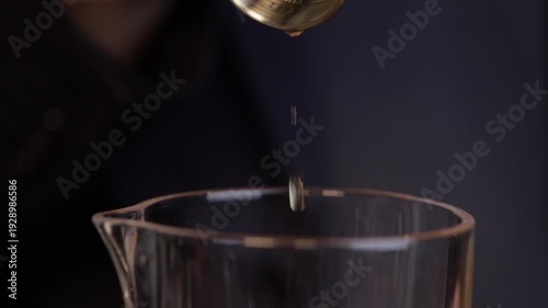 Bartender pouring bourbon whiskey into a mixing glass. Bartender preparing an old-fashionade cocktail.