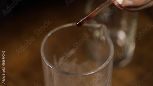 Bartender adding bitters to a mixing glass to prepare an old fashioned cocktail. Old fashioned drink.