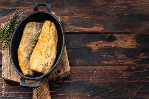 Bild auf Leinwand Crispy fried sea bass fish fillet with thyme in cast iron pan, mediterranean seafood dinner composition with rustic wooden background and copy space