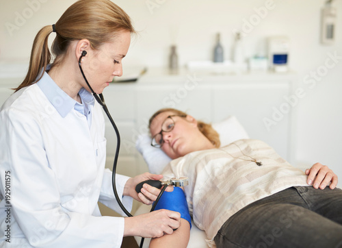 Female doctor taking blood pressure of patient in medical practice