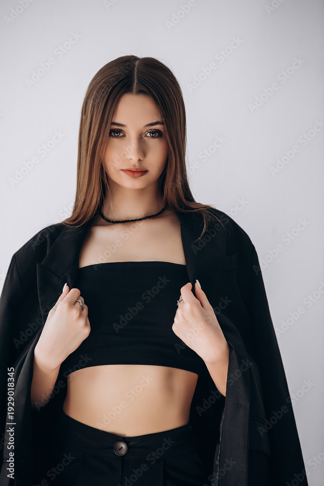 Naklejka premium Portrait of a model, a beautiful brunette girl with straight long hair in a black jacket on a white background