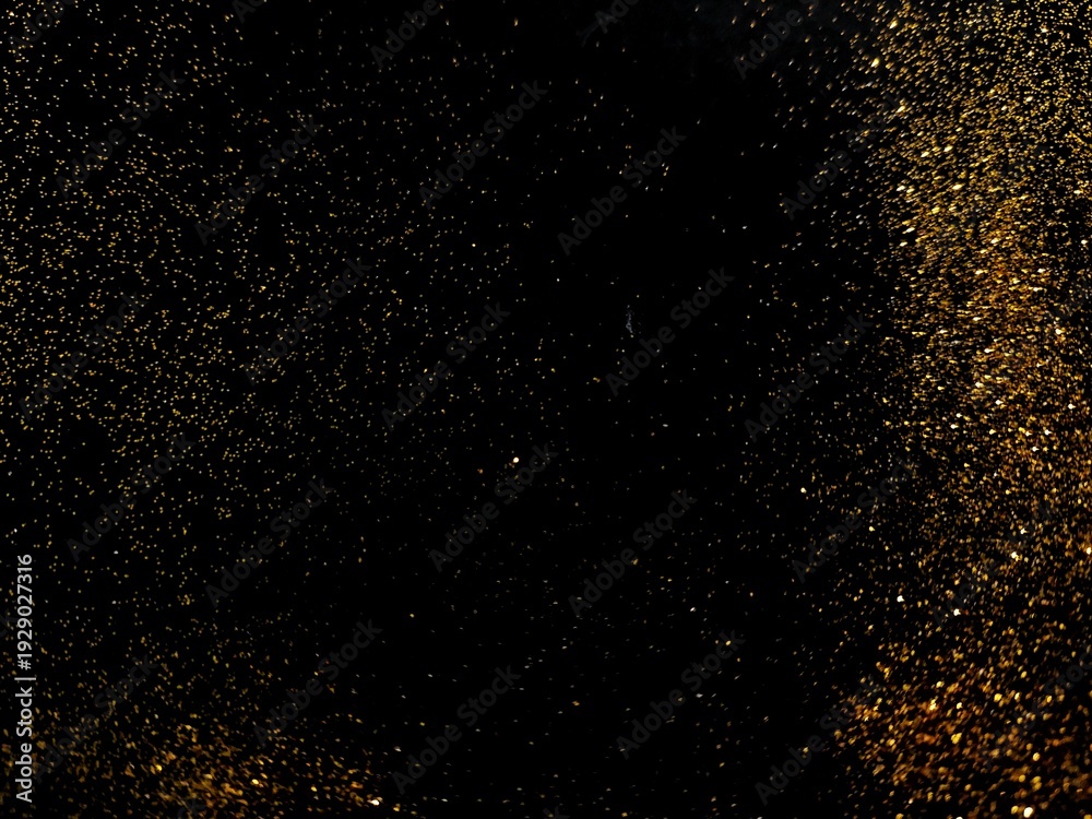 Obraz premium Abstract gold glitter particles sparkling on a black background. Luxury shiny black texture with glowing golden dust wave.