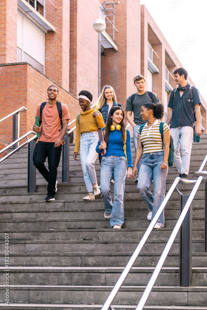 Obraz premium Diverse group of young students walking down urban university stairs together, enjoying college life and education
