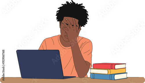 Stressed African American male student sitting at desk with laptop and books covering face with hand feeling exhausted.