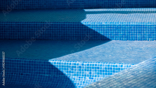 Blue mosaic tiled steps inside empty swimming pool