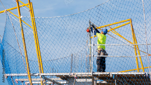 Construction worker installing safety net on scaffolding