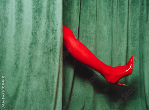 Red high heel leg emerges through green curtain in retro cabaret style