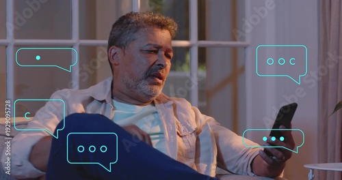 Holding phone, man in light shirt checking screen on living-room sofa at night, turquoise bubbles