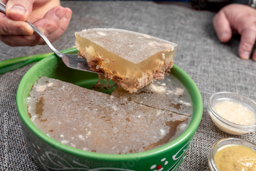 Closeup of authentic traditional Russian holodets (aspic jelly meat) served with mustard and fresh green onion, homemade food.
