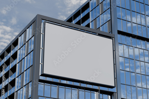 A large, blank billboard mounted on a sleek, modern skyscraper with numerous windows reflecting blue sky and white clouds
