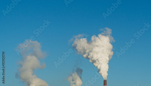 CO2, greenhouse gases emissions. CHP emissions. Smoking chimney releasing smoke against a blue sky. Smoke from factory pipe of heat station in the city. Air pollution. Nuclear power plant cooling.