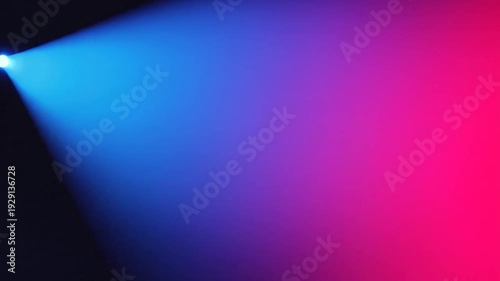 Bright blue spotlight beam illuminates a dark stage with a vibrant color