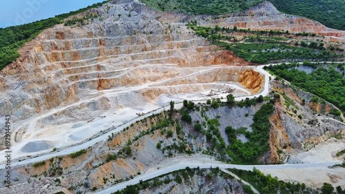 Quarry for extraction of minerals with equipment and machines, and road, in Rhodope Mountains covered with forests