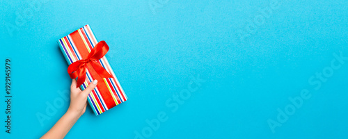 Wallpaper Mural Woman arms holding gift box with colored ribbon on blue table background, top view and copy space for you design Torontodigital.ca