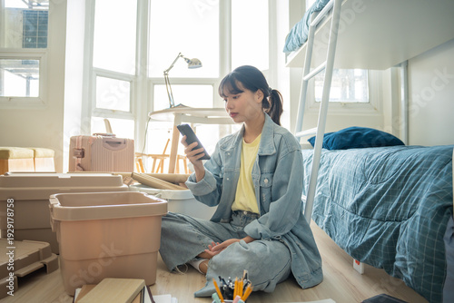Фотография Student asian woman organize room unpack in dorm room college student moving to new  university dormitory or preparing to move out