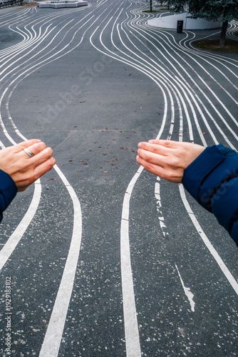 Canvas Print Close Up of Hands Separating White Wavy Lines on Black Asphalt, Superkilen Park,